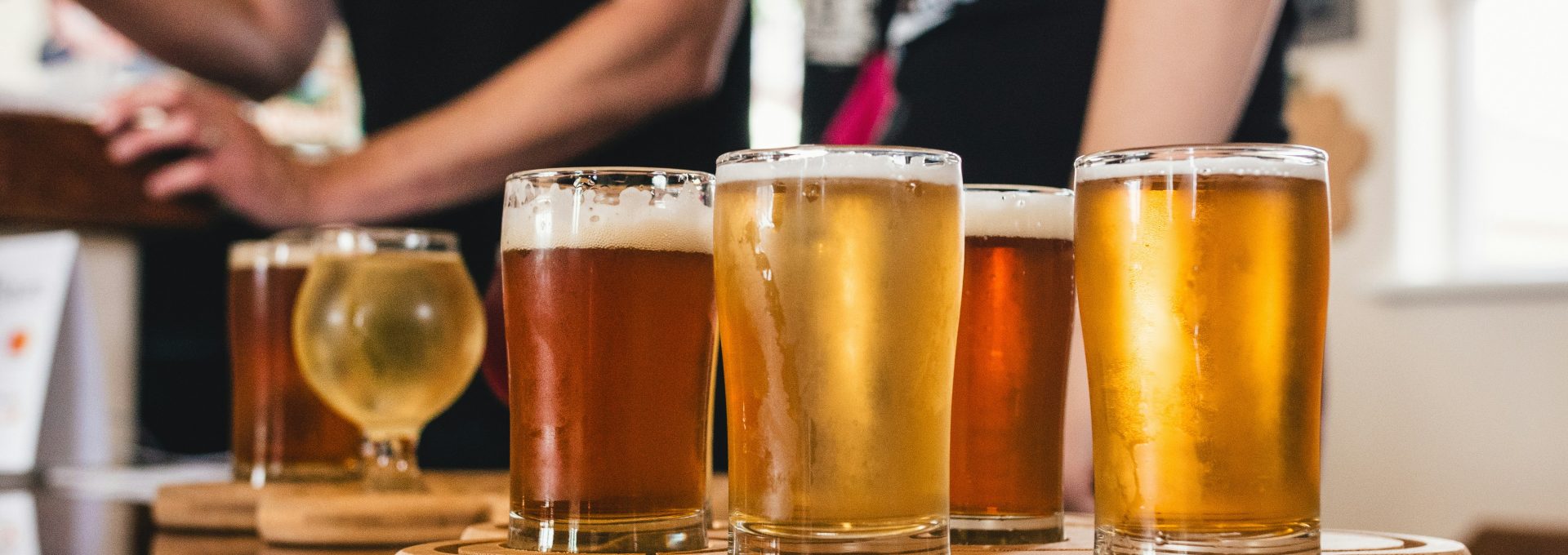 a group of people are standing around a wooden table with beer glasses at The  Campbell