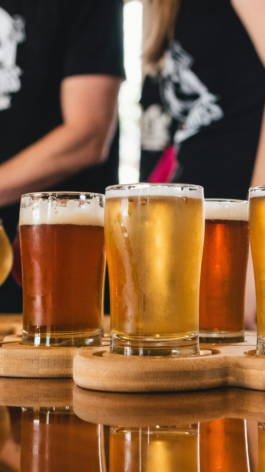 a group of people are standing around a wooden table with beer glasses at The  Campbell